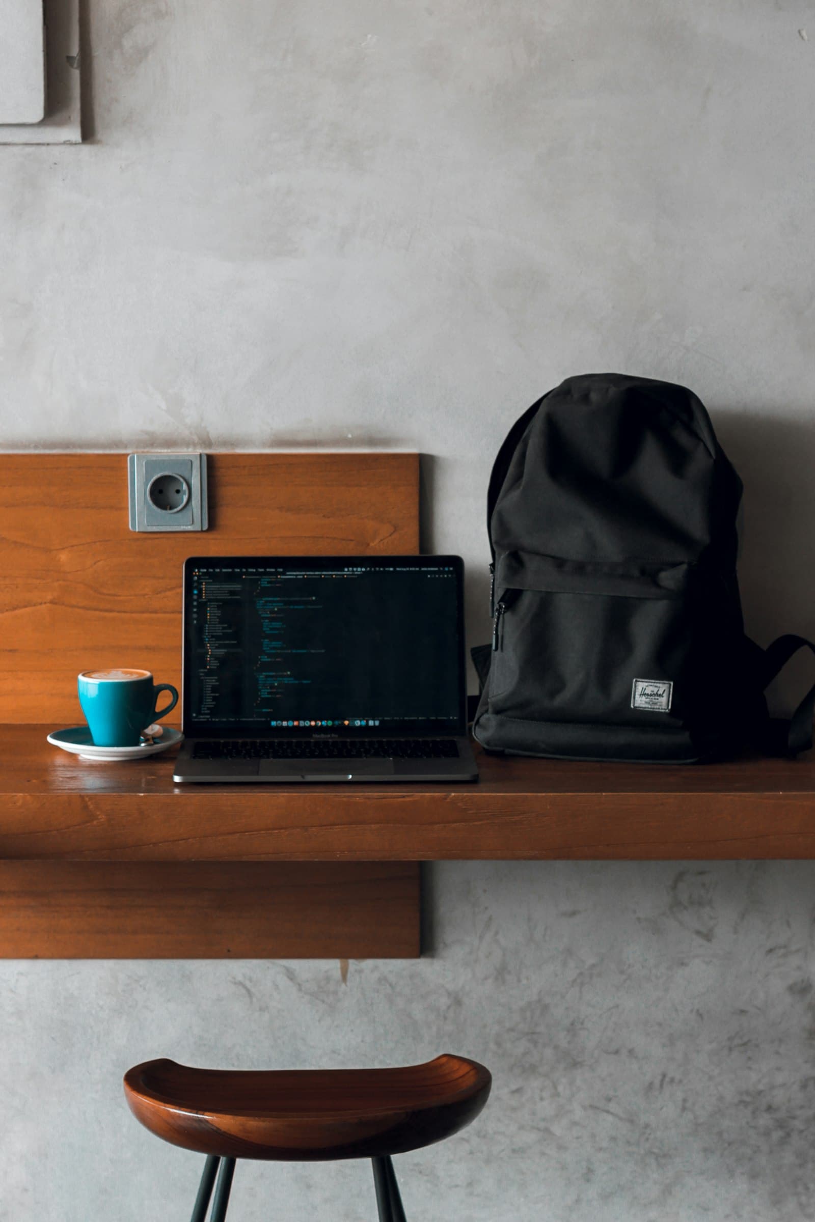 Laptop computer beside backpack and coffee mug